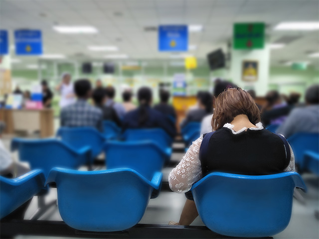 A busy hospital emergency waiting room, with many of the chairs filled with patients.