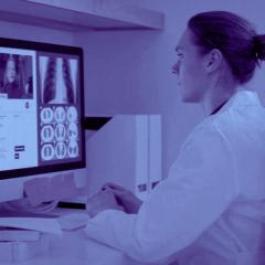 doctor conducting telehealth session with monitor showing patient and medical imaging