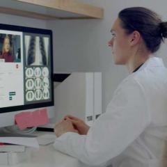 Female doctor doing a telehealth conference with x-rays and other diagnostics on her screen. 