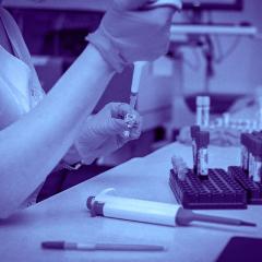 woman researcher putting blood in test tubes in a lab for genetic testing.