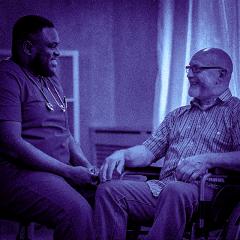 Male nurse sitting with patient in wheelchair