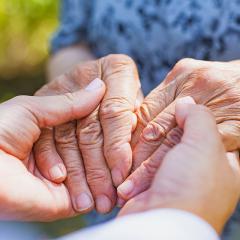 Close up of an older set of hands holding a younger set of hands