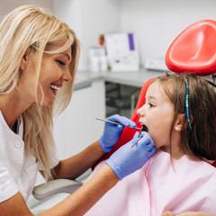 small girl in a dentists chair being treated by a female dentist